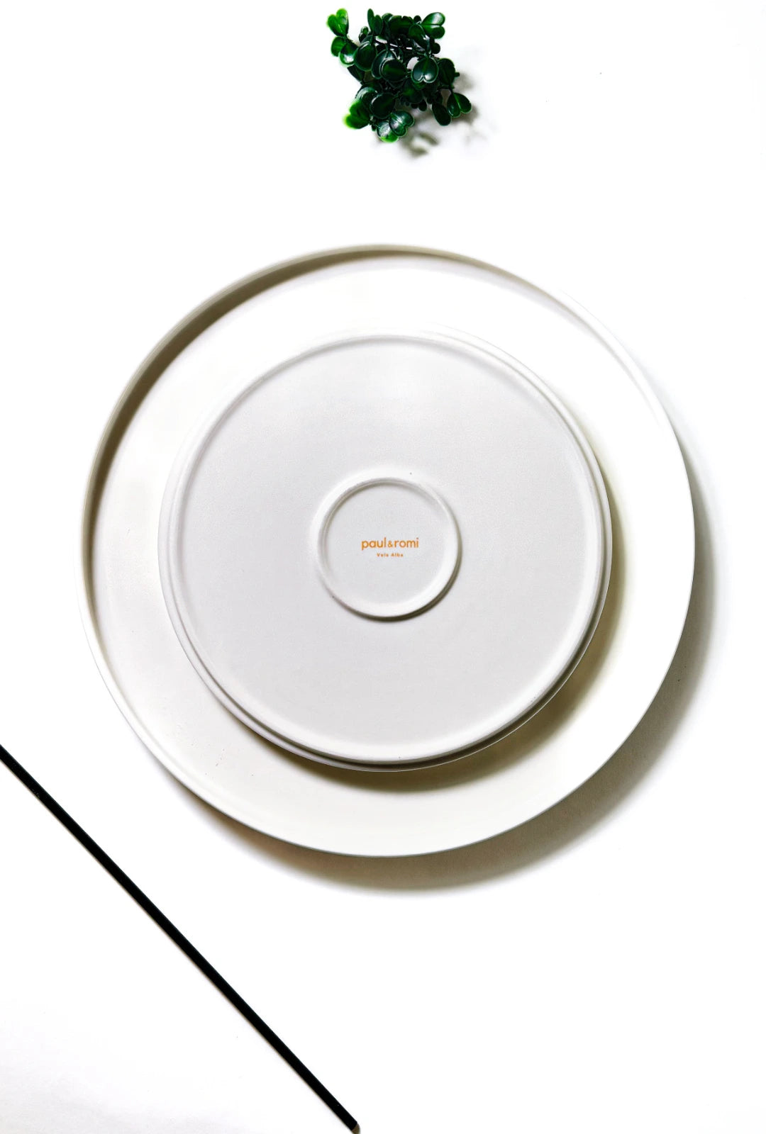 Overhead view of a white Vela Alba small plate set with nested plates and paul&romi logo