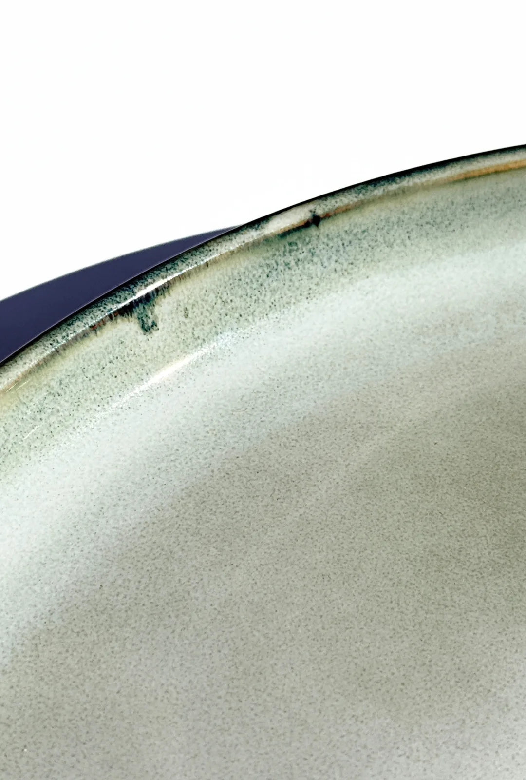 Close up of a Nordic Forest plate edge with speckled gray glaze and dark rim.
