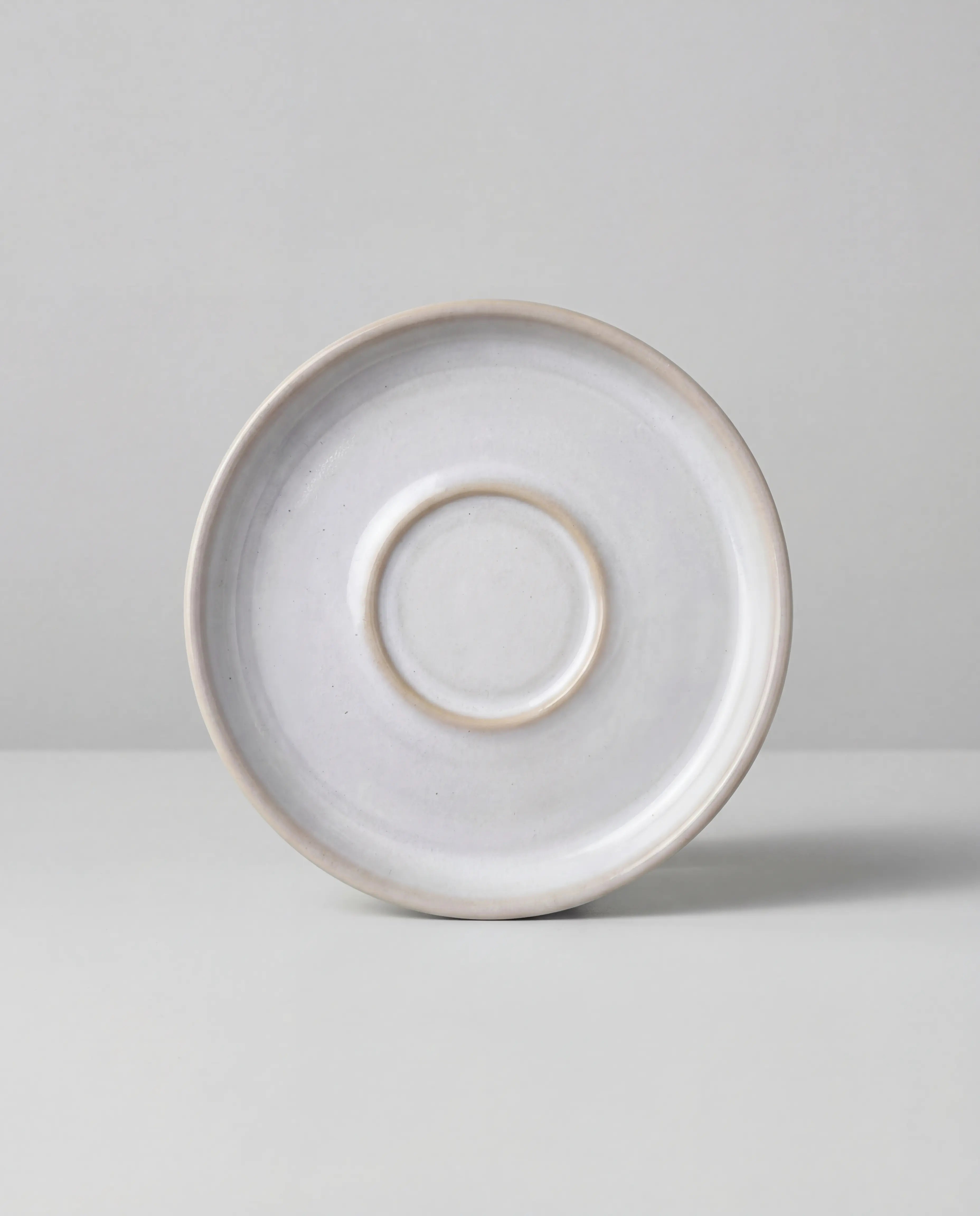 Lyra white ceramic saucer viewed from above with a subtle rim