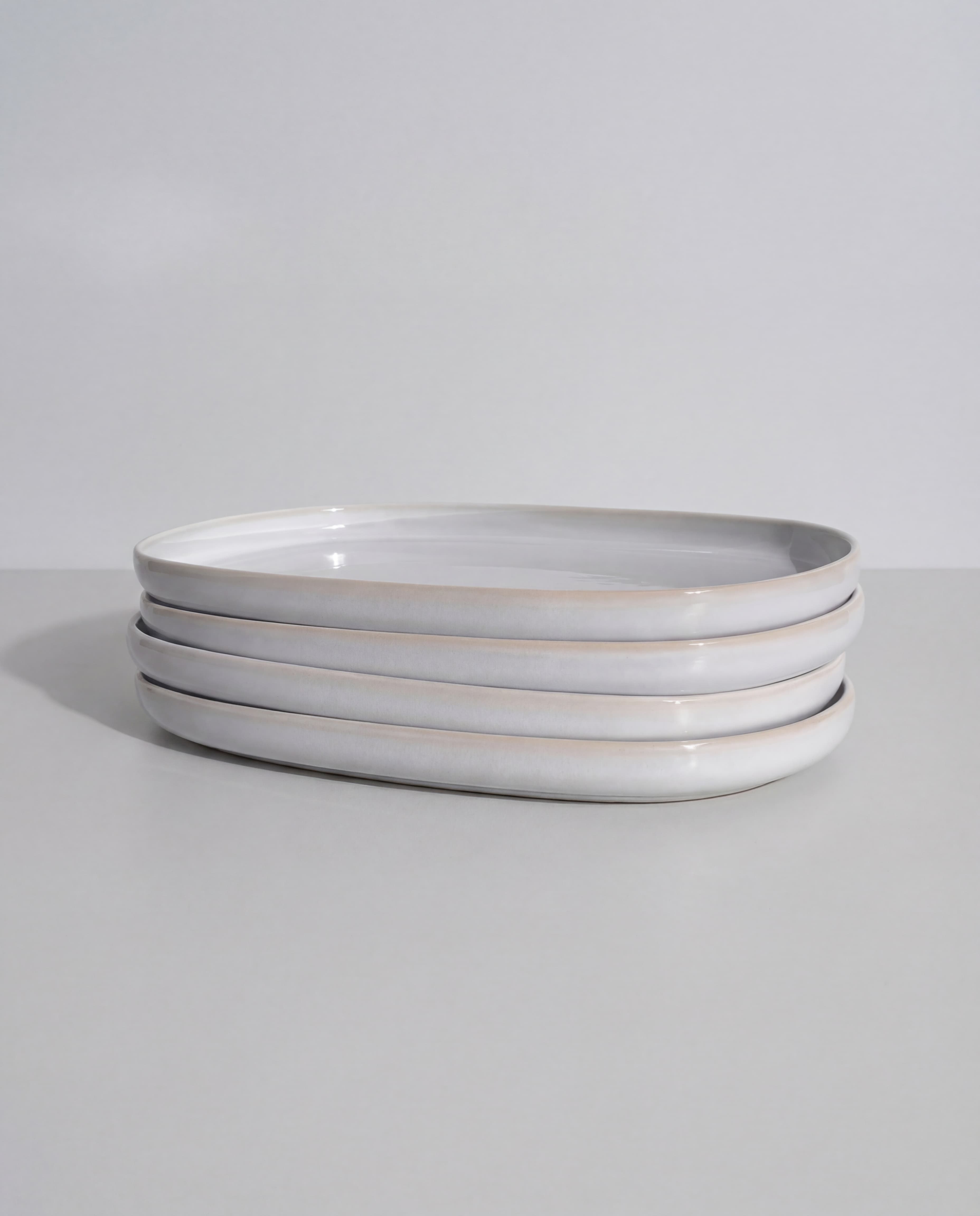 Stack of four white serving plates from the Lyra ceramic collection