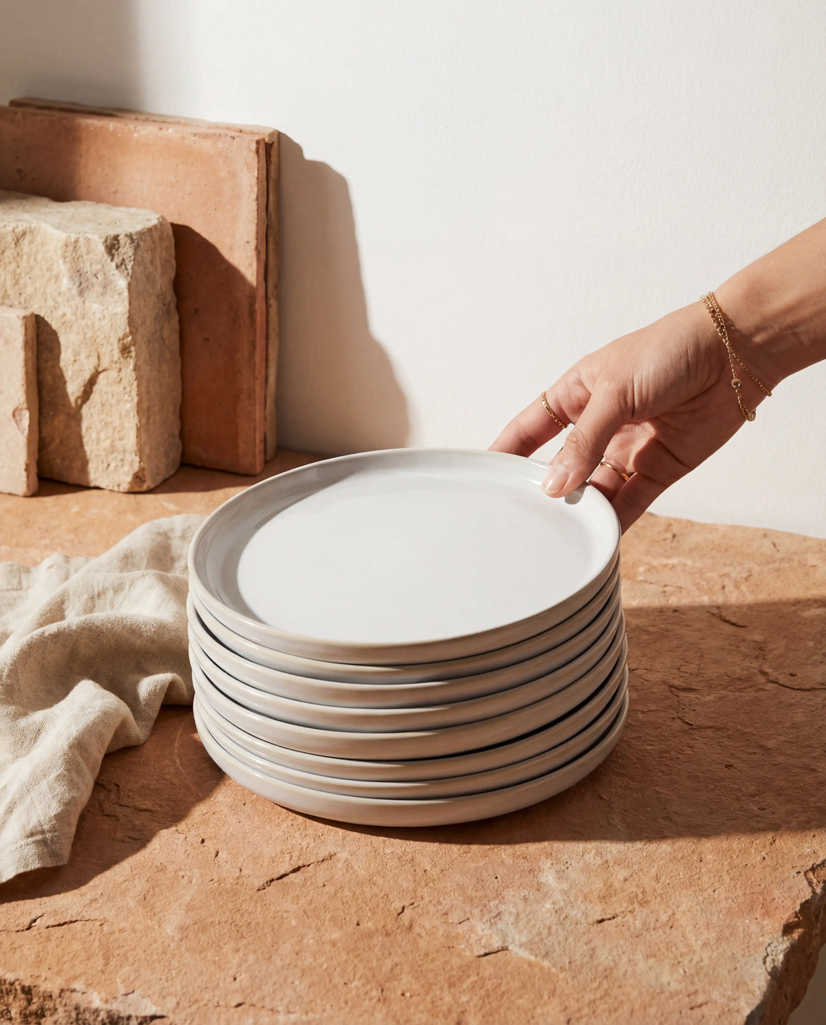Close up of a white Lyra dessert plate with a smooth curved rim on a stone surface