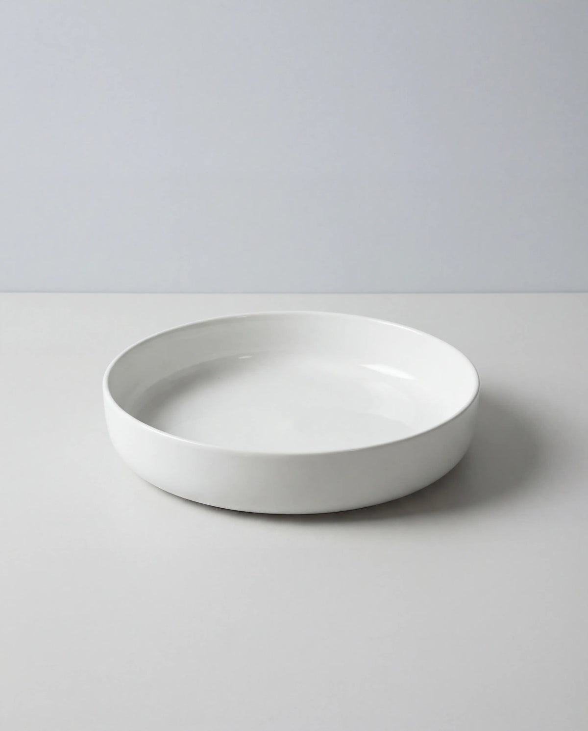 White round pasta plate partially visible at the bottom of the frame against a pale grey background