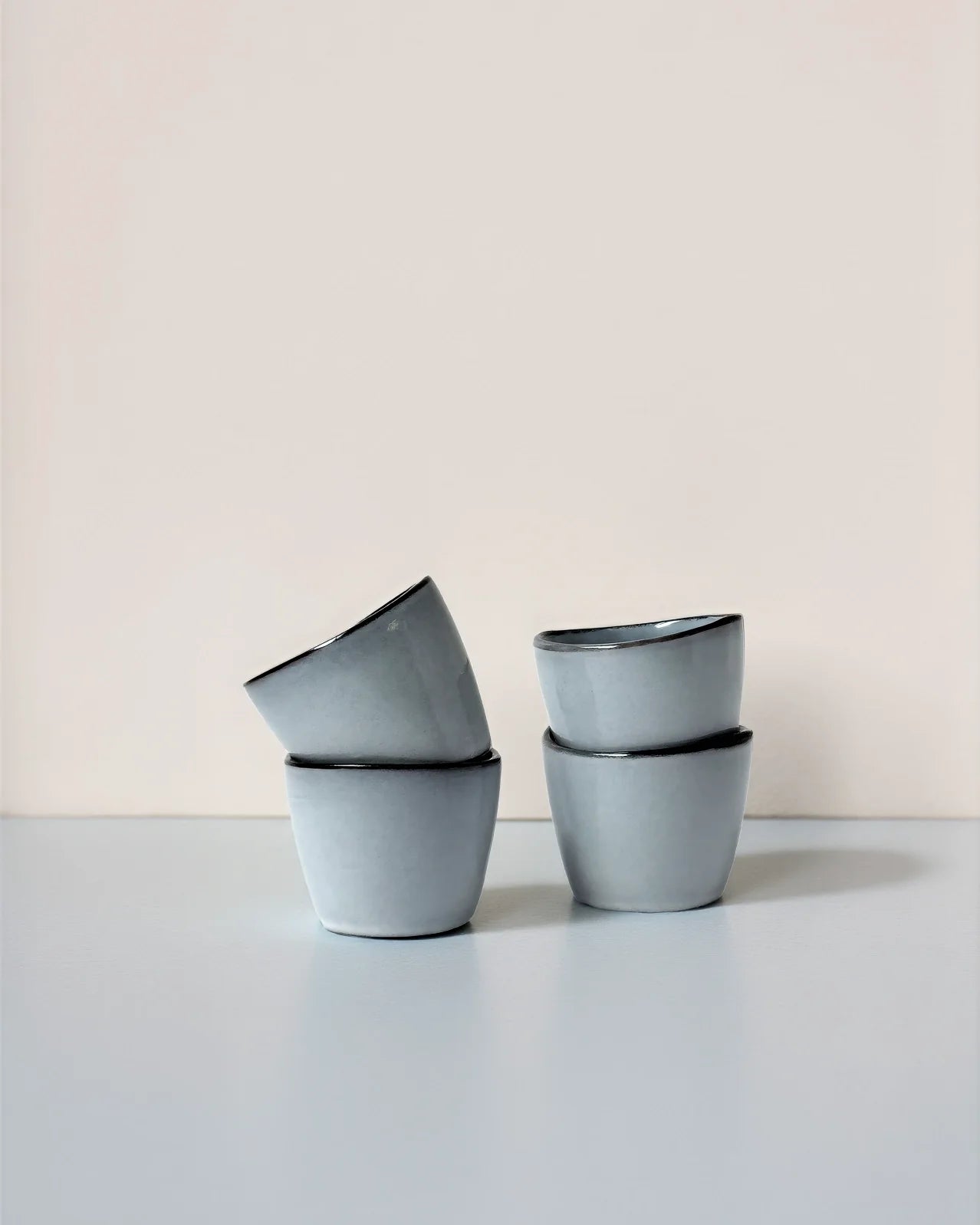 Close up view of four blue Nordic Fjord Dip espresso cups with dark rims on a light surface