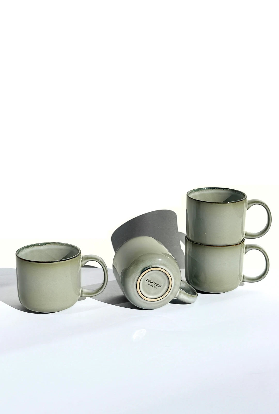 Nordic Forest ceramic mugs arranged in a still life, one mug on its side to show the base