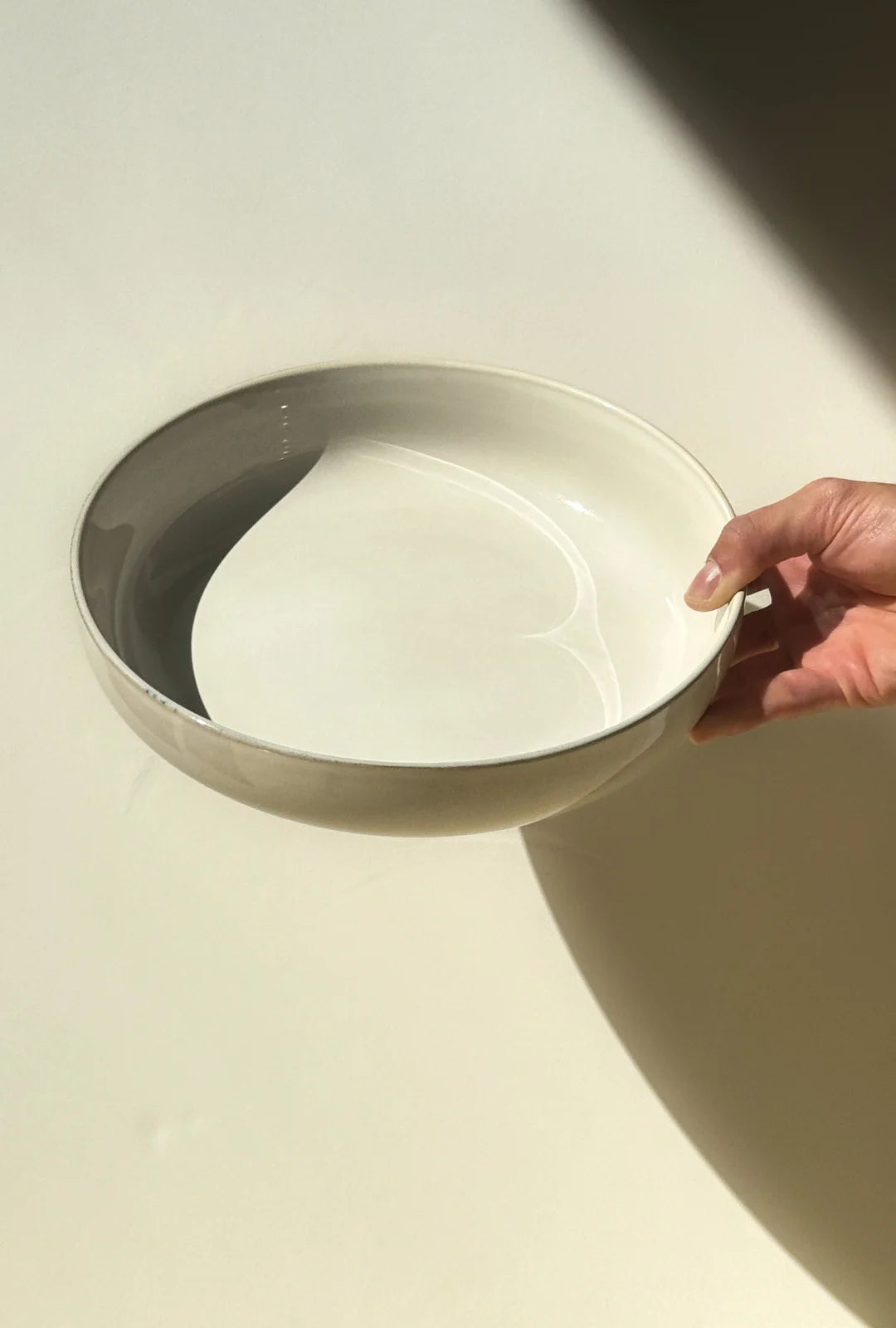 Scandic Sails Servierschale white porcelain bowl with curved inner divider held by a hand