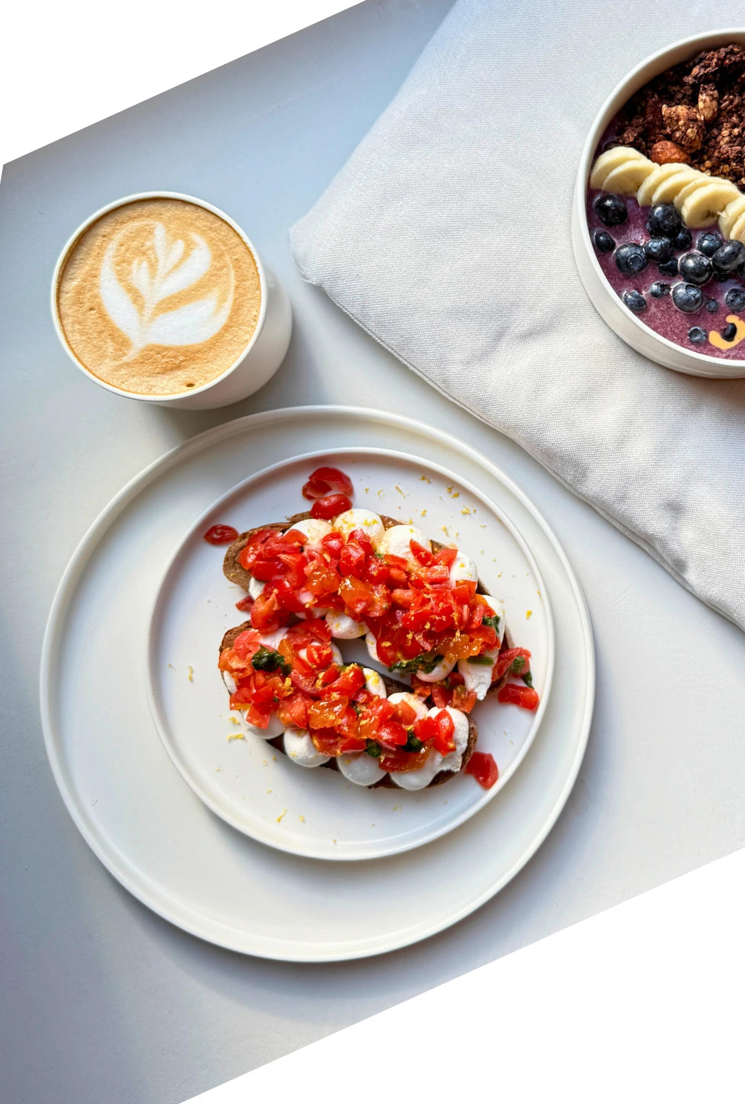 Vela Alba small plate with tomato bruschetta and a latte on a light surface