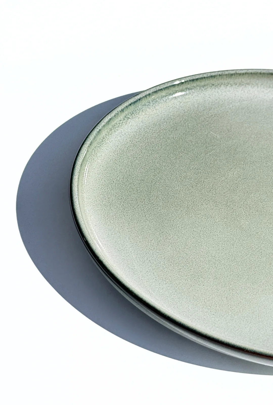 Close up of a Nordic Forest plate showing a speckled light gray glaze and smooth rim