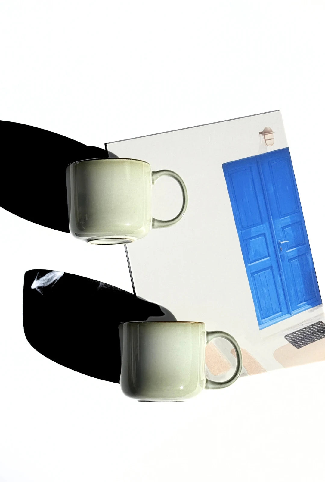 Grey Nordic Forest mug resting on a magazine page featuring a blue door illustration