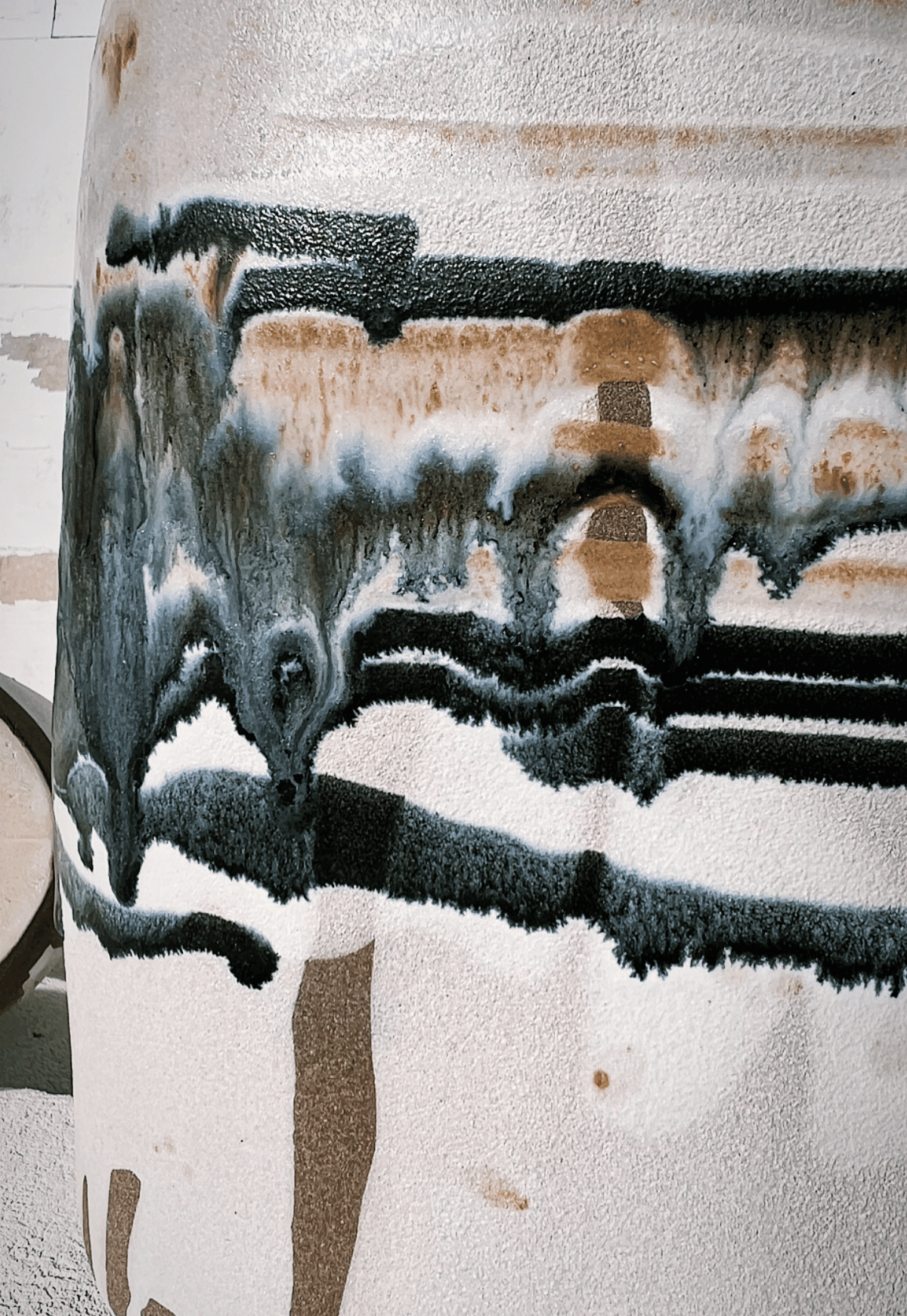 Side view of Boa Tarde Vase with beige glaze and bold black blue drip patterns