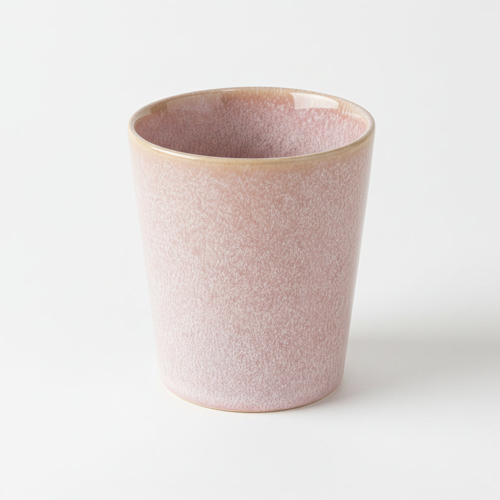 Pink speckled ceramic coffee cup with a pale beige rim on a white background
