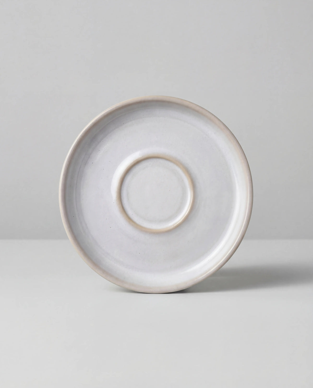 Lyra white ceramic saucer viewed from above with a subtle rim