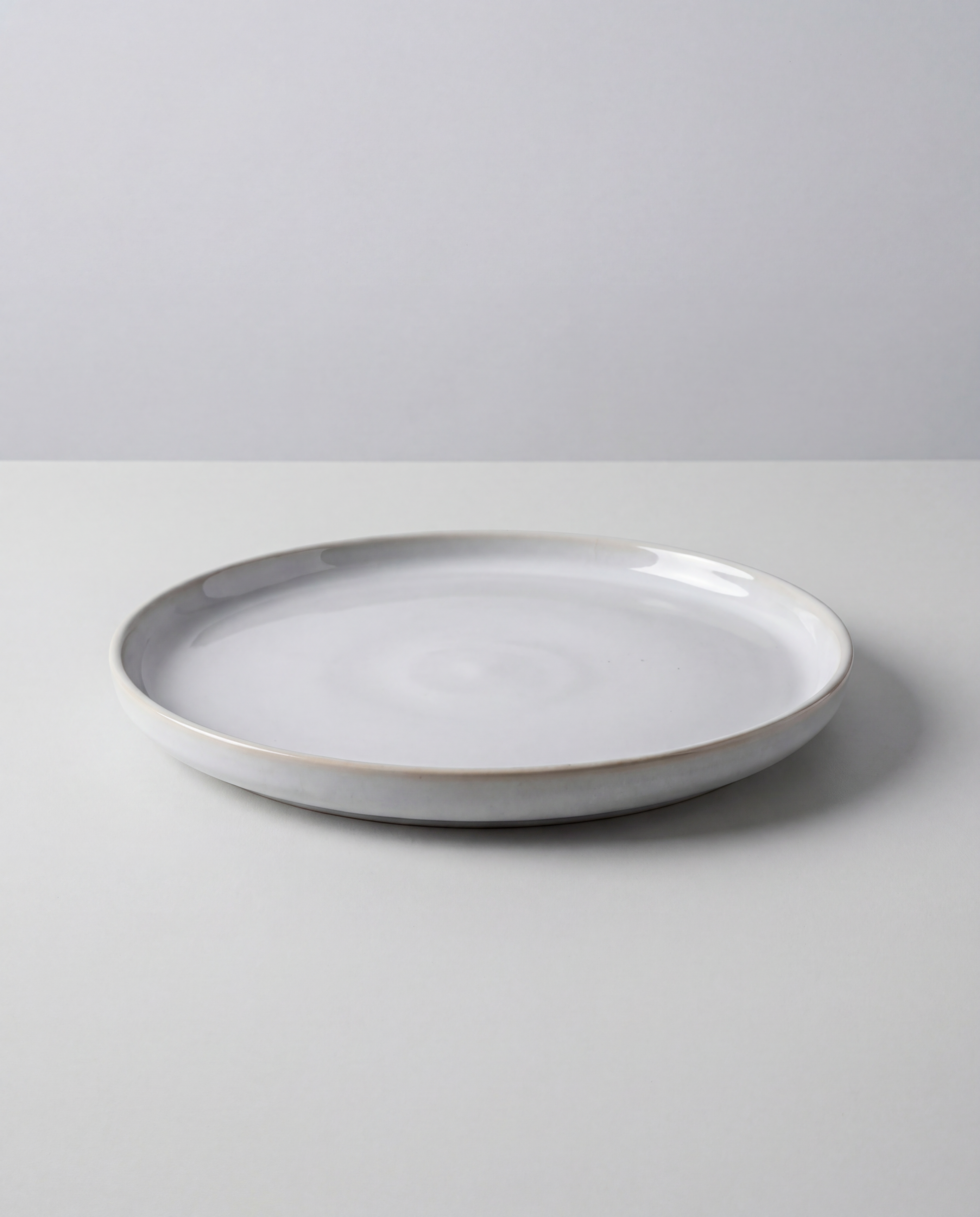 White ceramic dinner plate from Lyra set with smooth glaze and curved rim