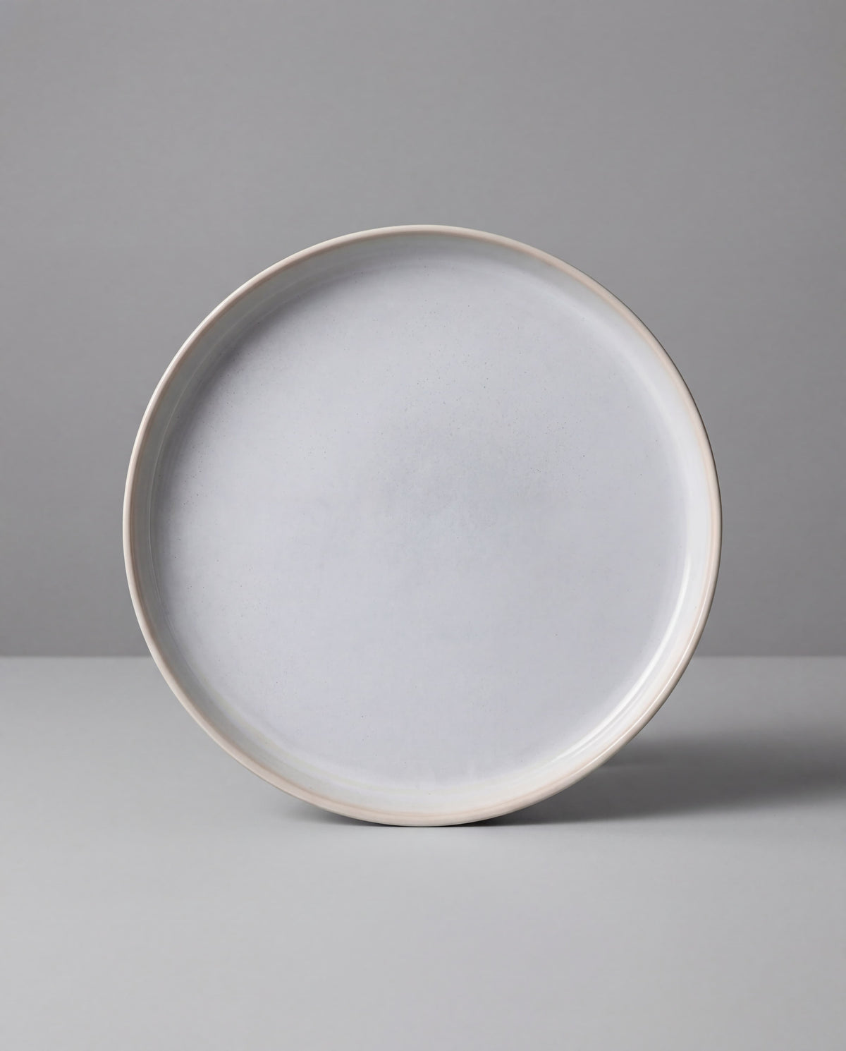 Edge view of a pale gray speckled ceramic plate from the Lyra Geschirrset 40+2 piece set