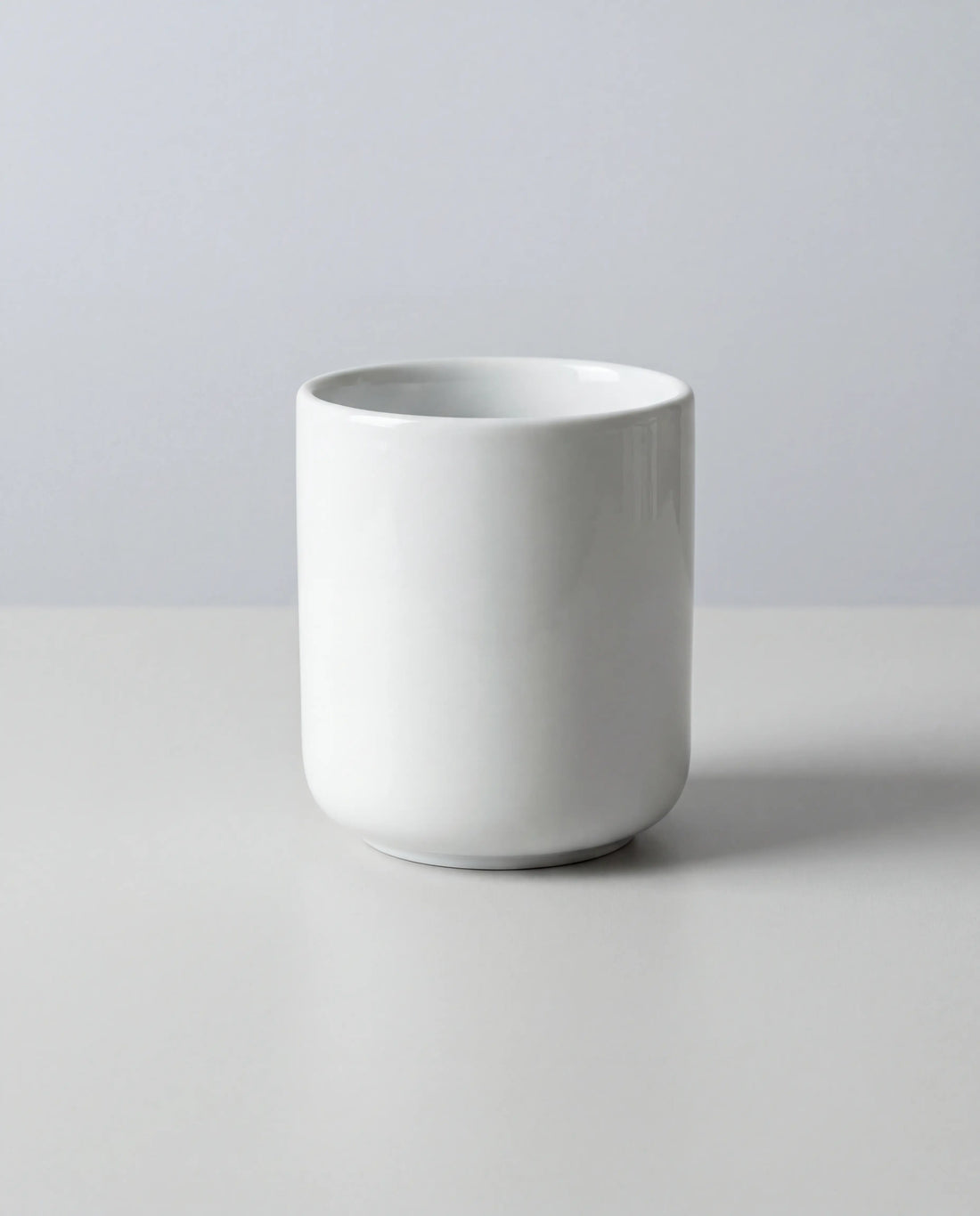 Close-up of a white porcelain espresso cup against a soft gray backdrop.
