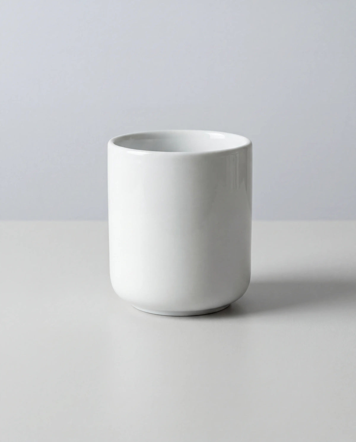 Close-up of a white porcelain espresso cup against a soft gray backdrop.