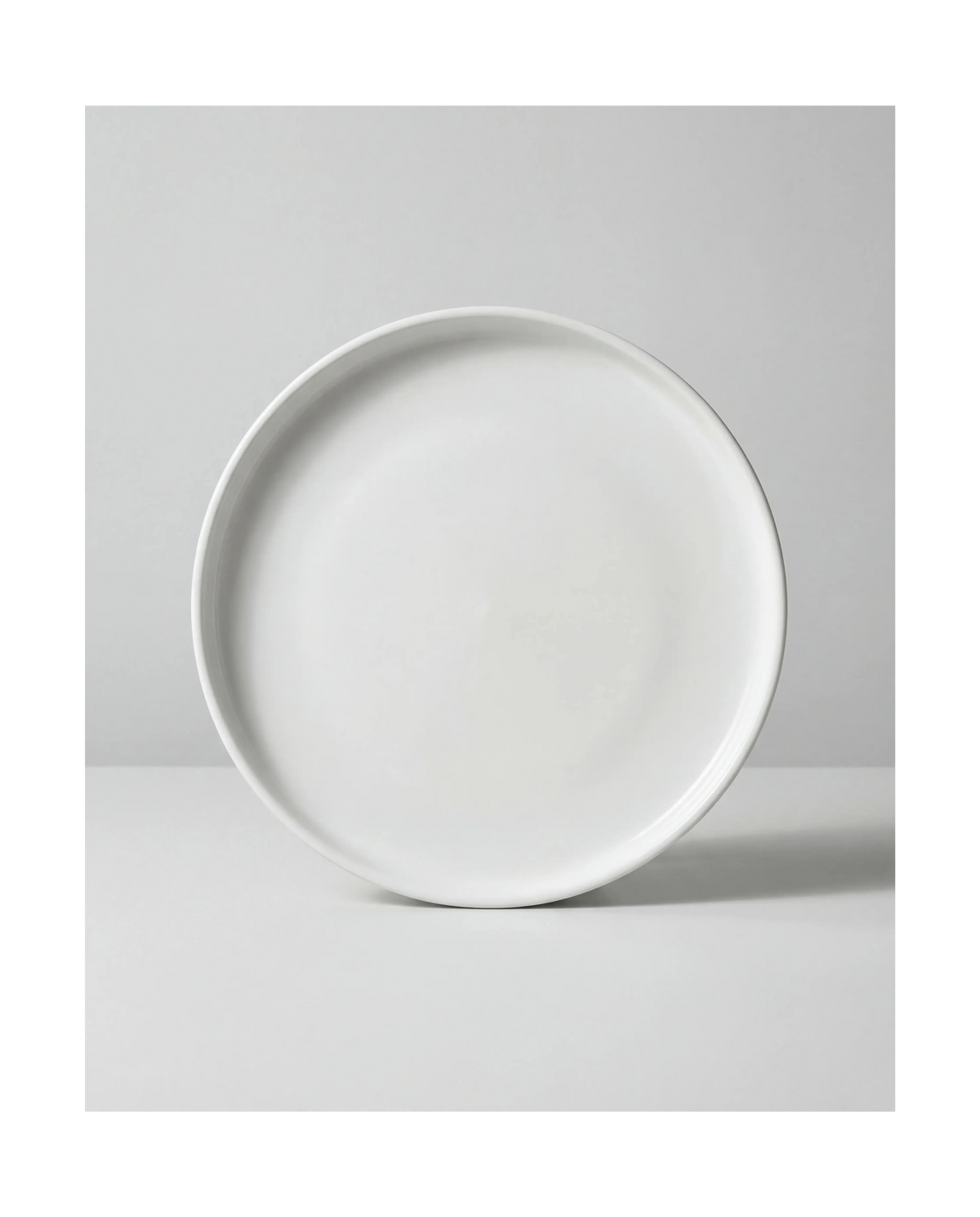 Close up of a large white plate from the Vela Alba 48 piece dish set on a light gray backdrop
