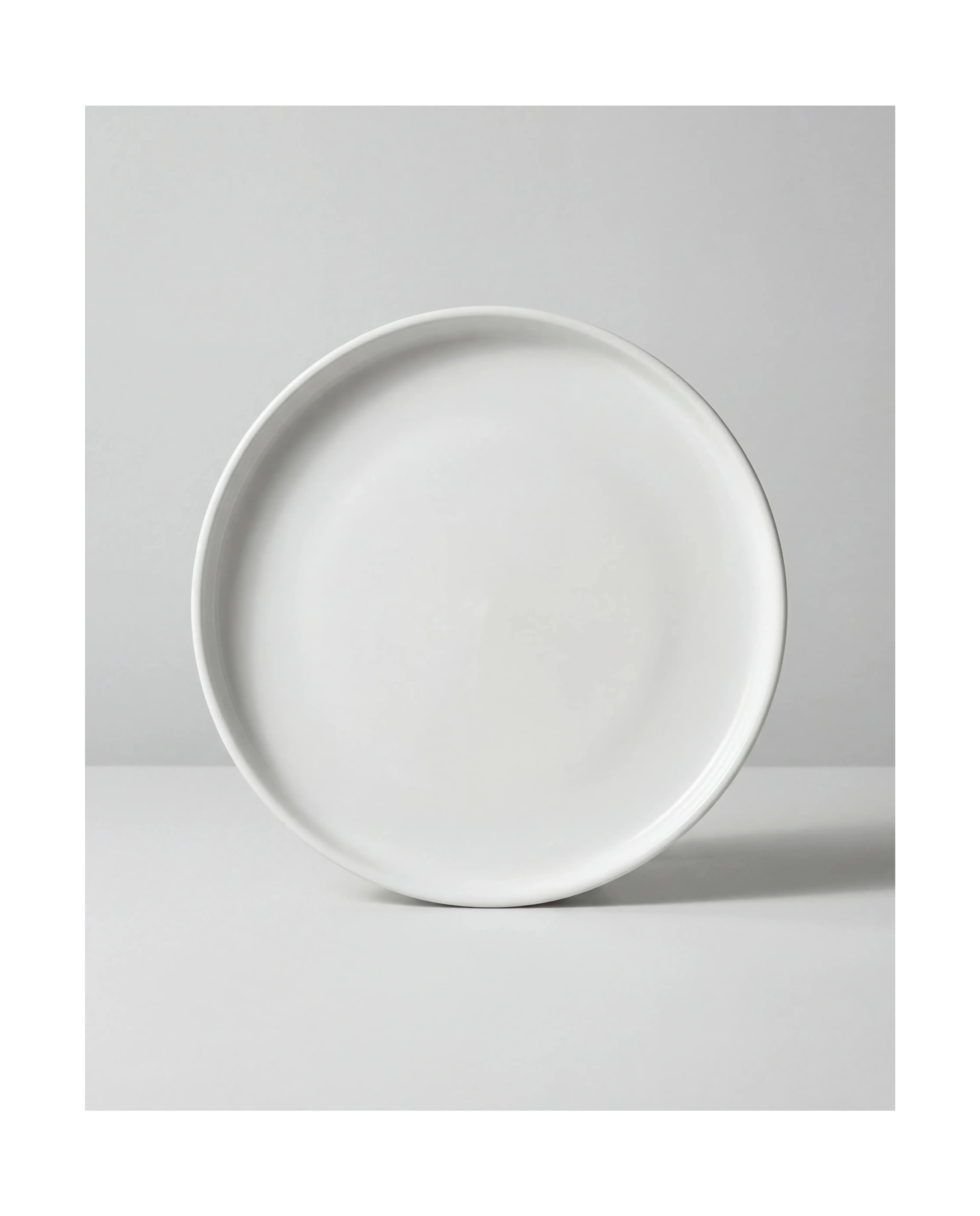 Close up of a large white plate from the Vela Alba 48 piece dish set on a light gray backdrop