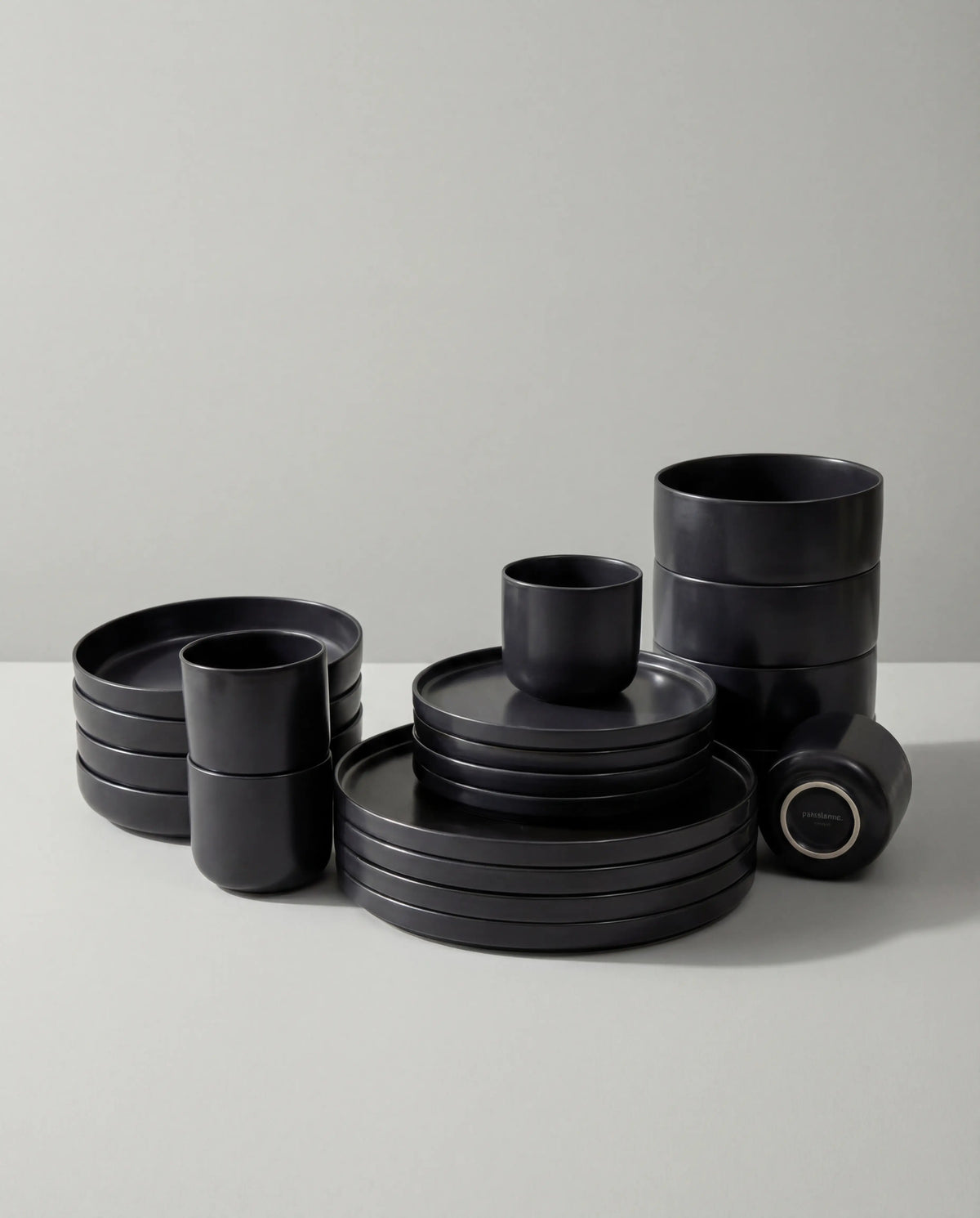 Vela Luna 20 piece black matte dinnerware set stacked on a white surface