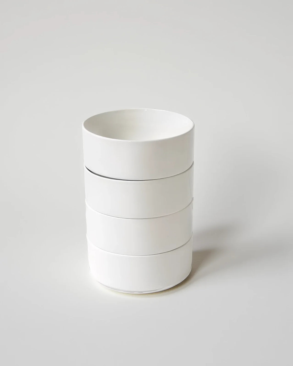 Tall stack of white bowls with straight sides and glossy glaze