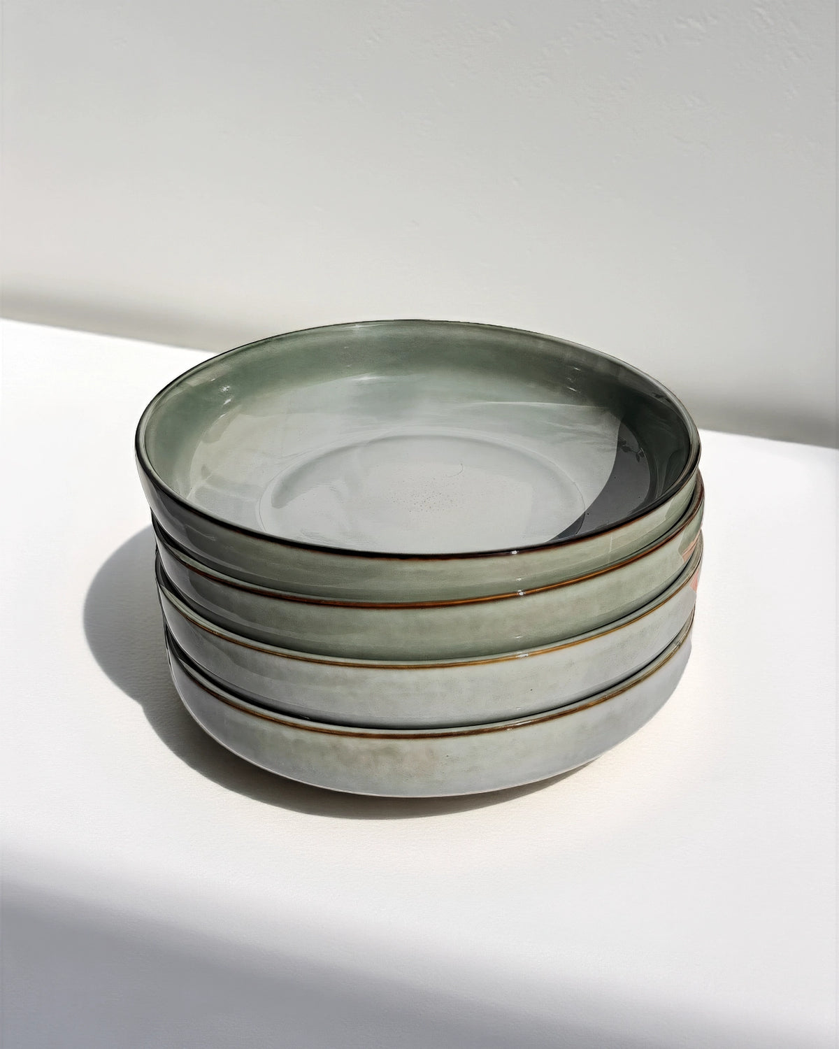 Stack of Scandic Soul Nordic Forest pasta plates in muted gray green glaze.