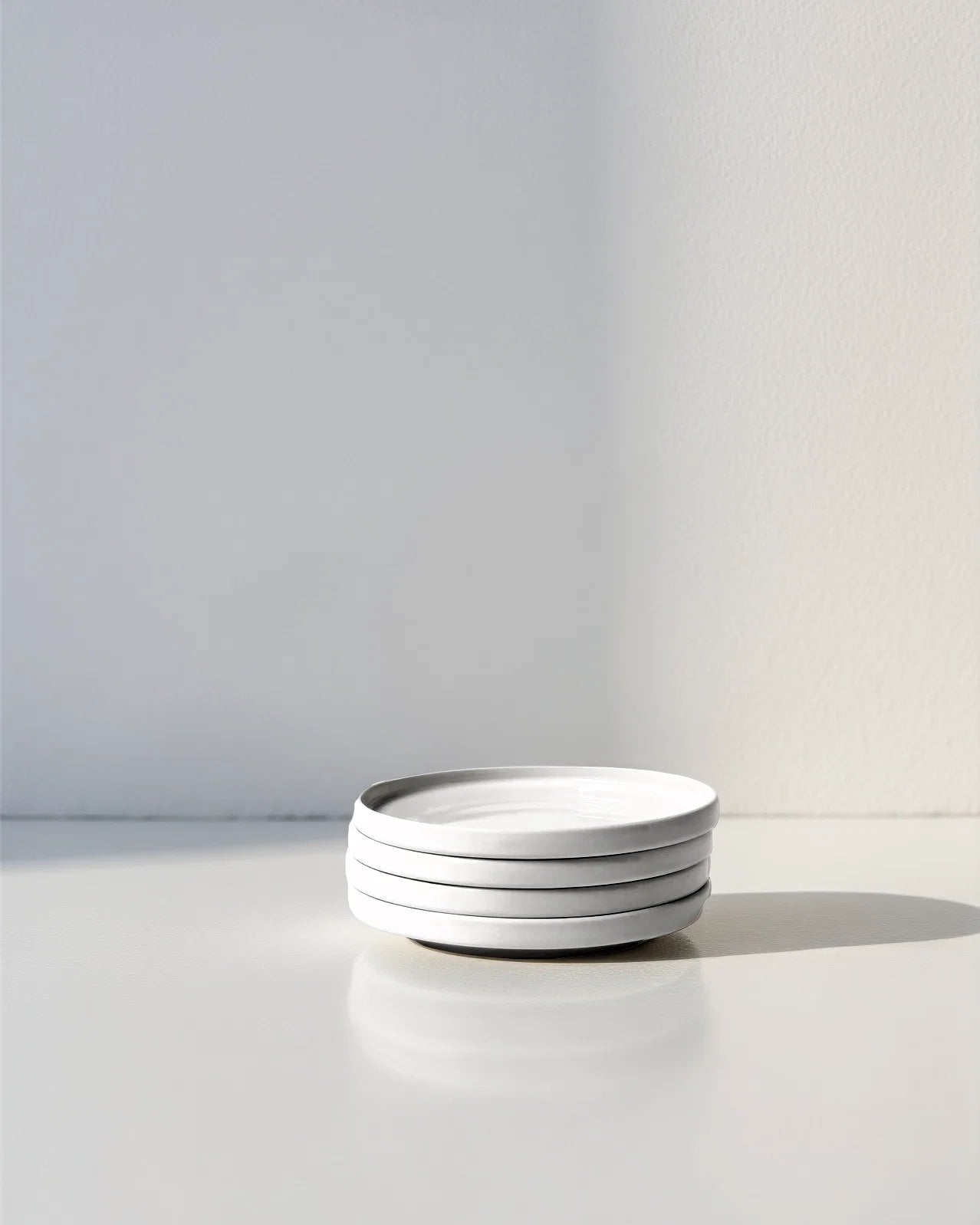 Stack of white plates with a dark glaze edge from Hugo Kaffeemomente Set on a light surface.