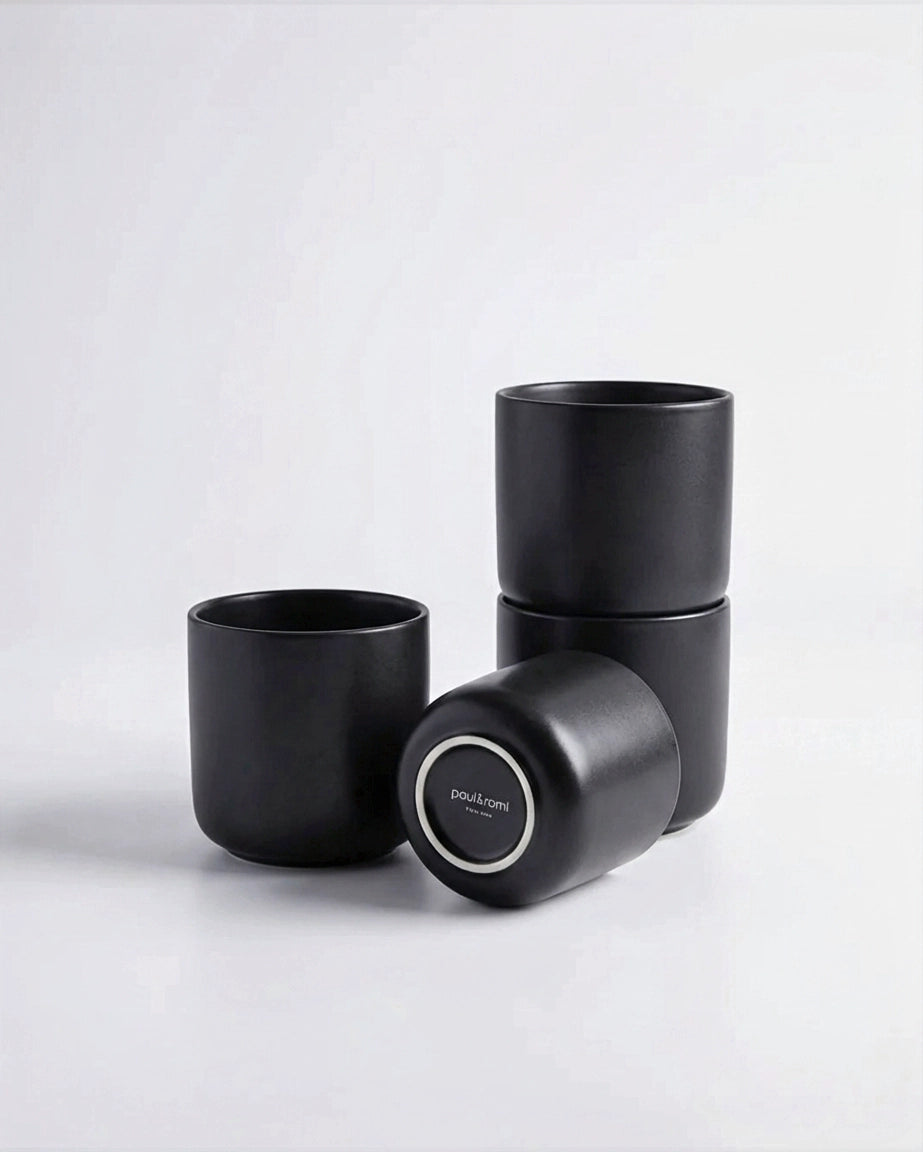 Vela Luna Becher four piece set of black matte cups stacked with one cup resting on its side