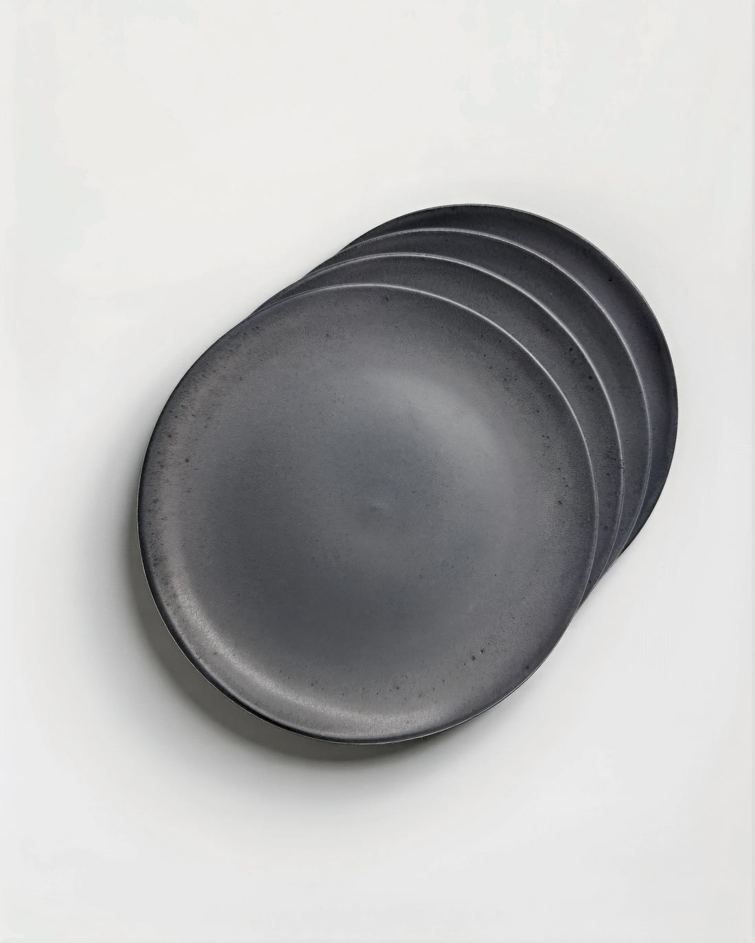 Stacked dark gray plates on a white background