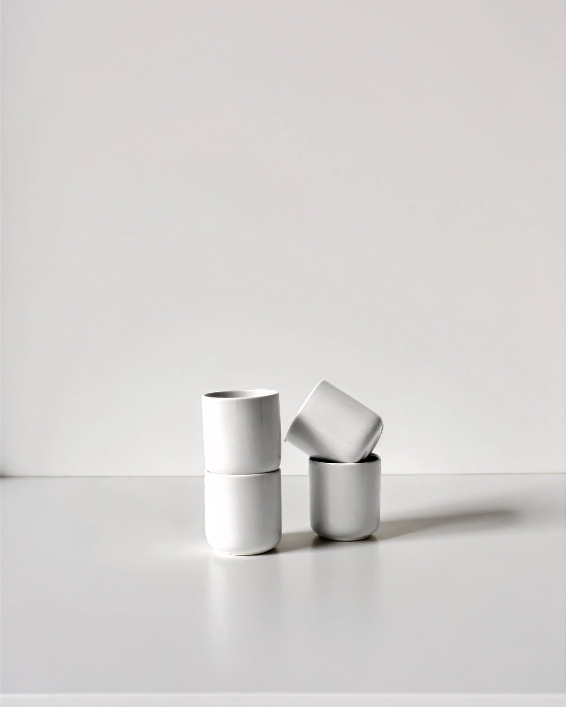 Six white espresso cups arranged in a neat cluster on a clean white surface