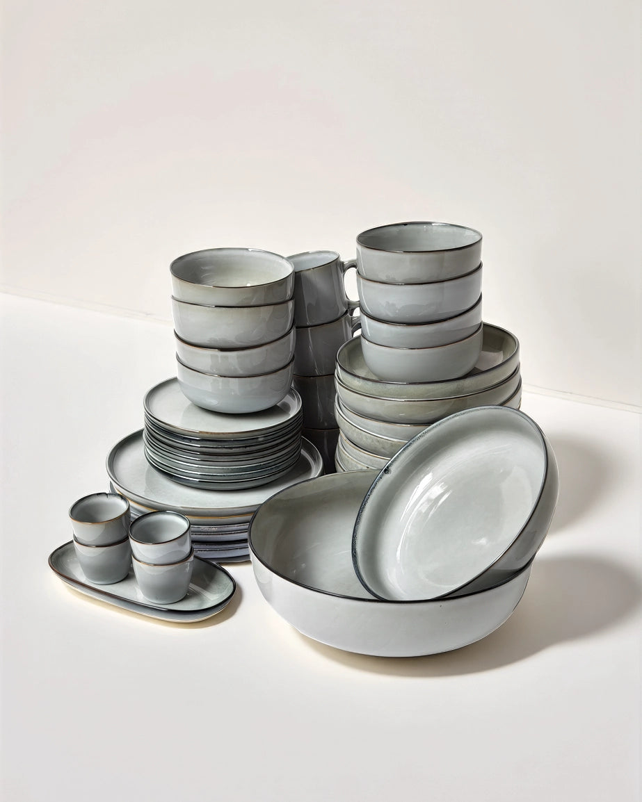 Nordic Forest bowls and plates in pale gray blue with dark rims stacked for display