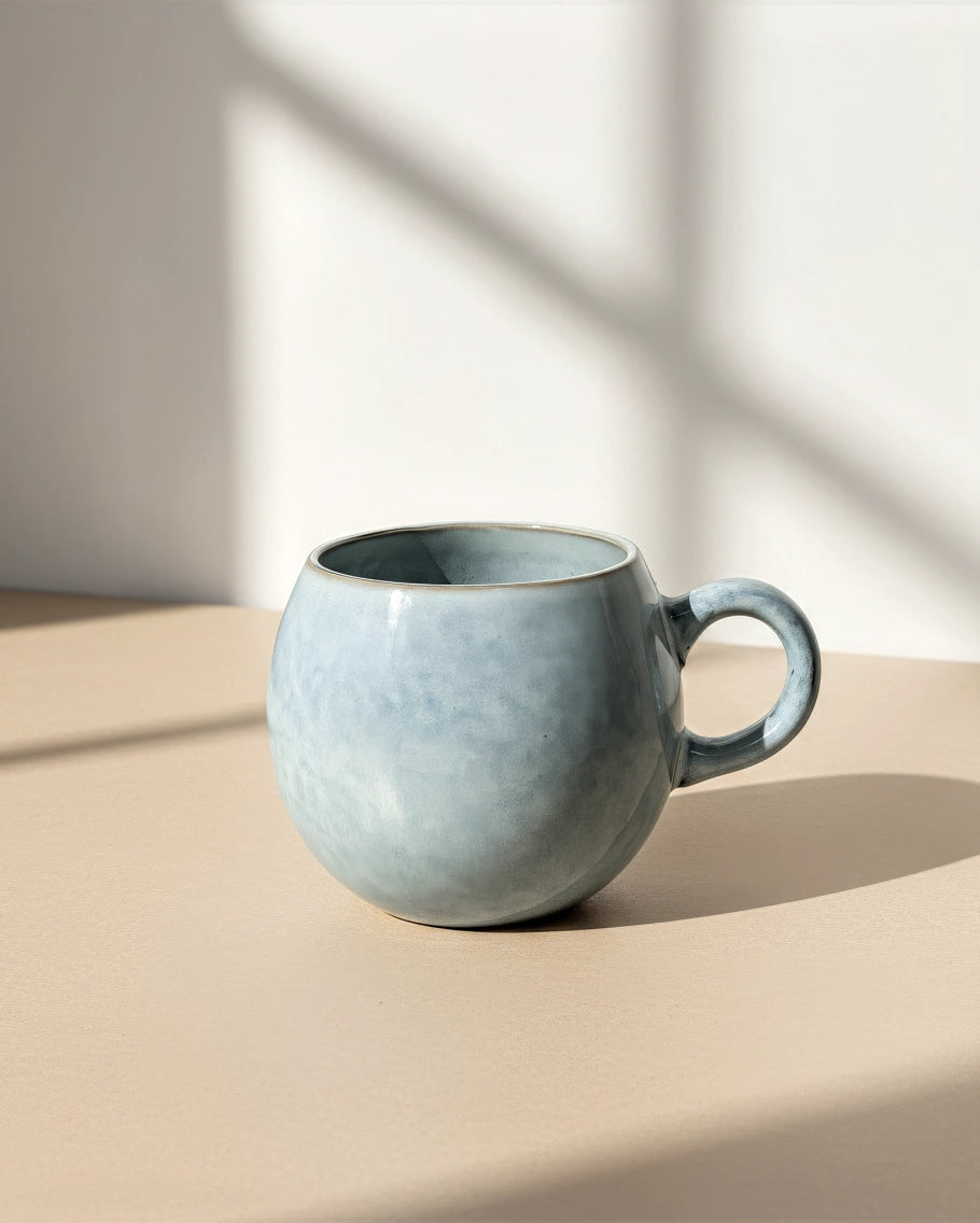 Nordic Fjord Bauchtasse mug with rounded belly and blue grey glaze on a light beige surface