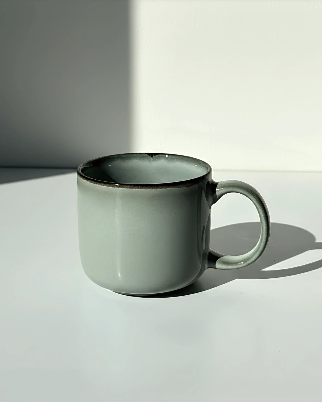 Scandic Soul mug in Nordic Forest glaze with a pale green gray body and dark rim.