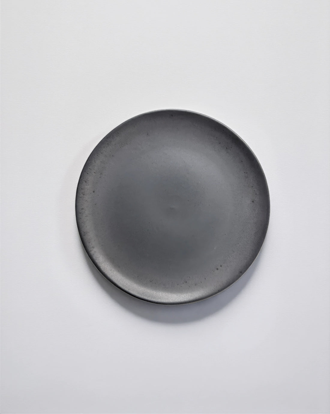 Single matte grey dessert plate viewed from above on a white background.