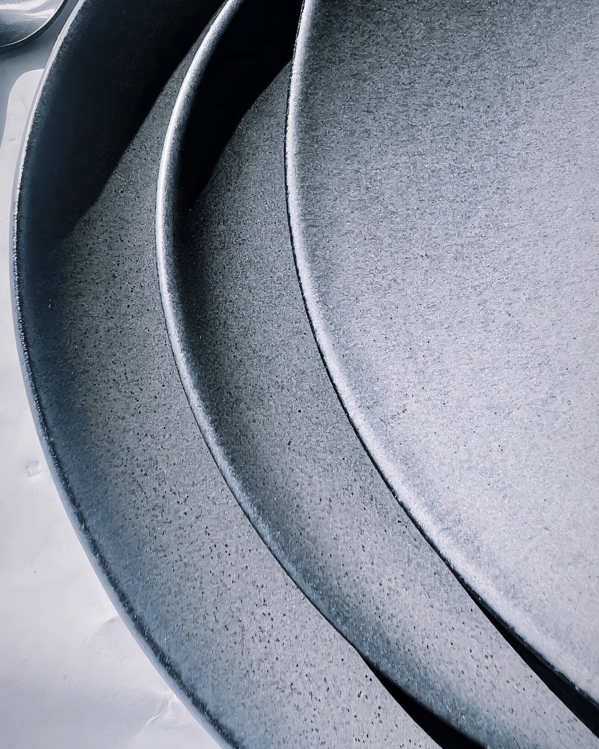 Close-up of a textured dark grey speckled dinner plate with a worn finish.