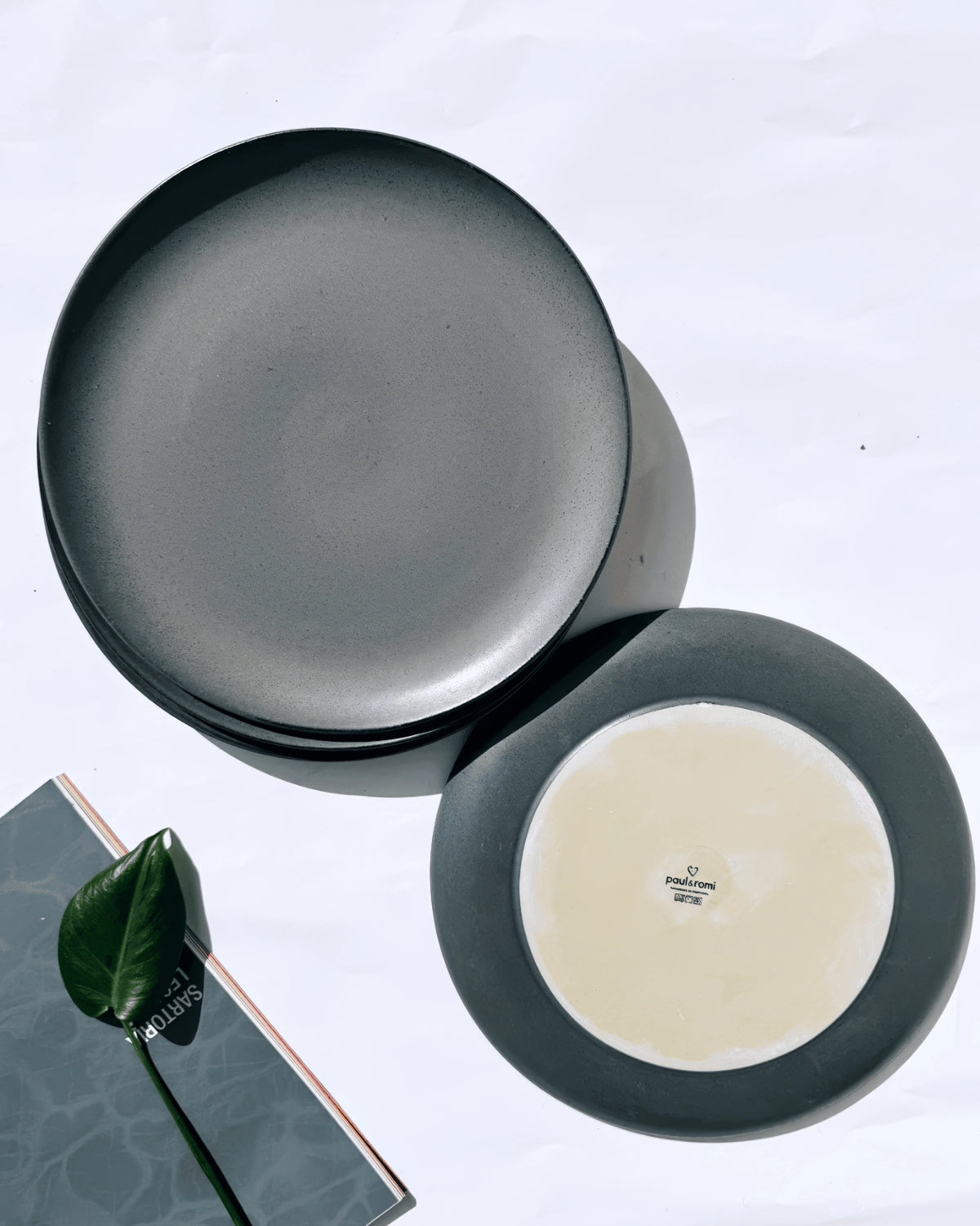 Boa Noite dessert plate with dark gray rim and pale center shown among other plates