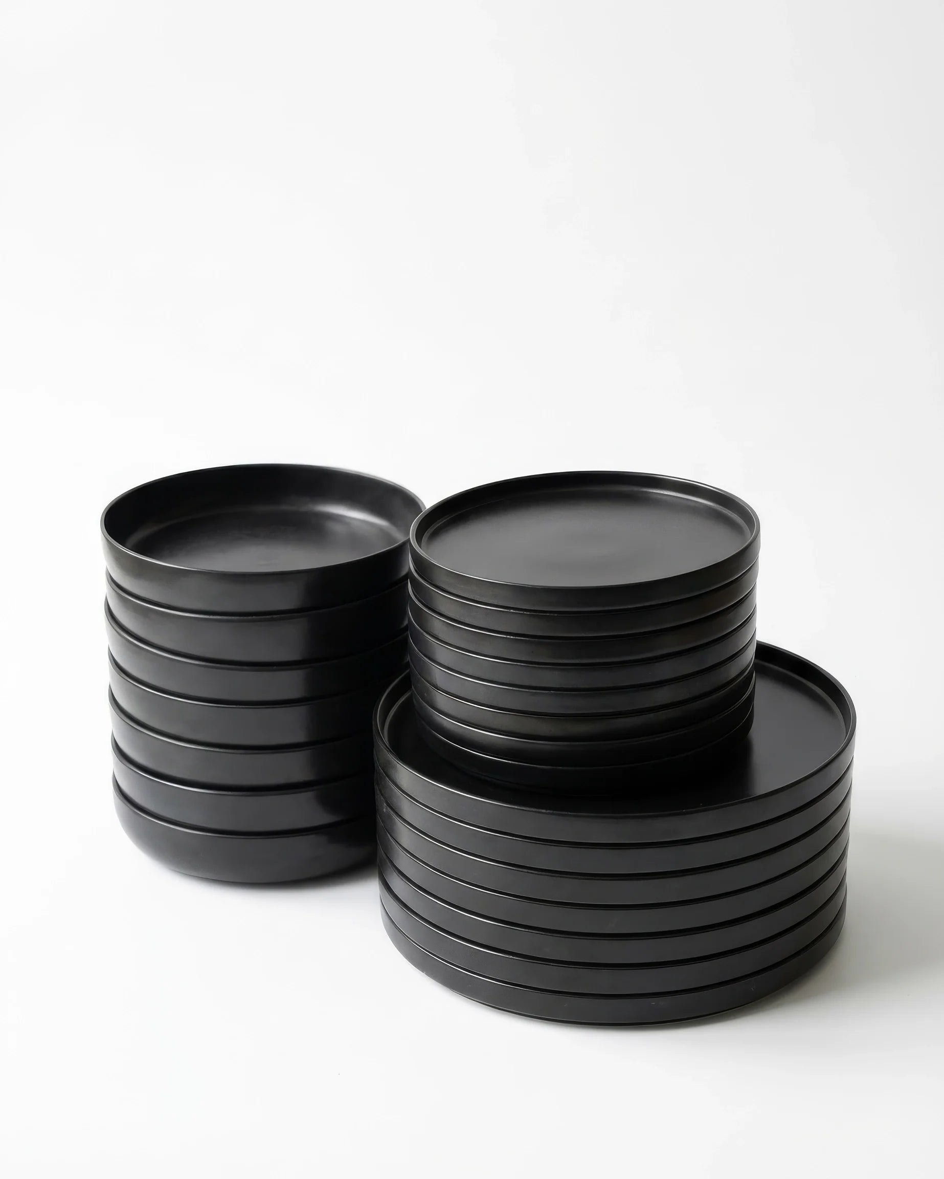 Stack of black matte plates from the Vela Luna 24 piece dinnerware set